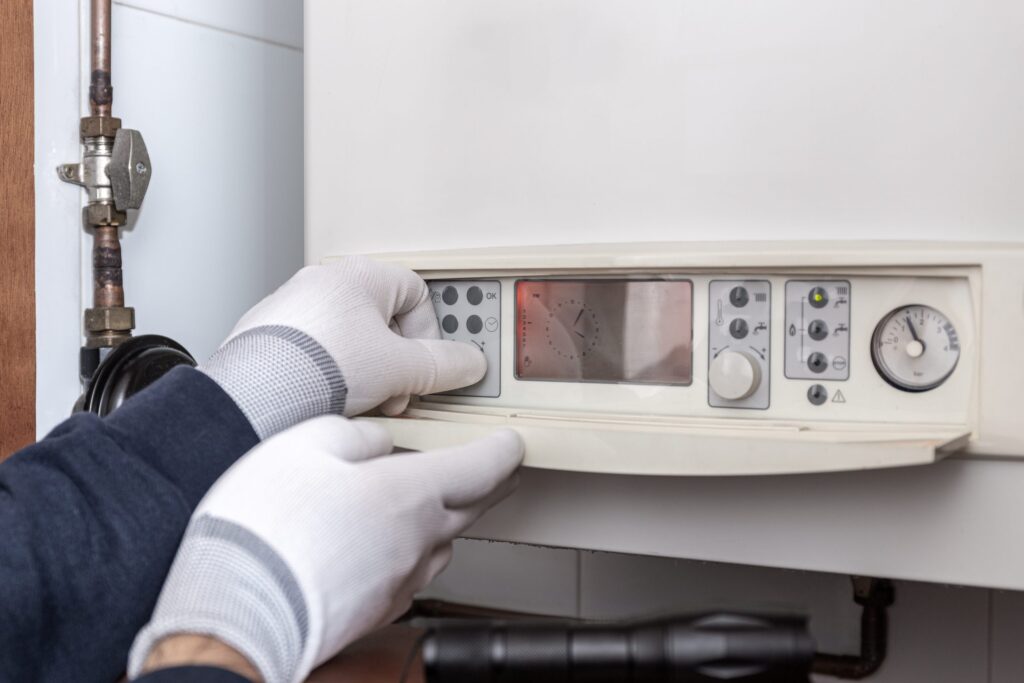 Technician servicing heating boiler in a house. Maintenance concept Fix my boiler pressure in Acton